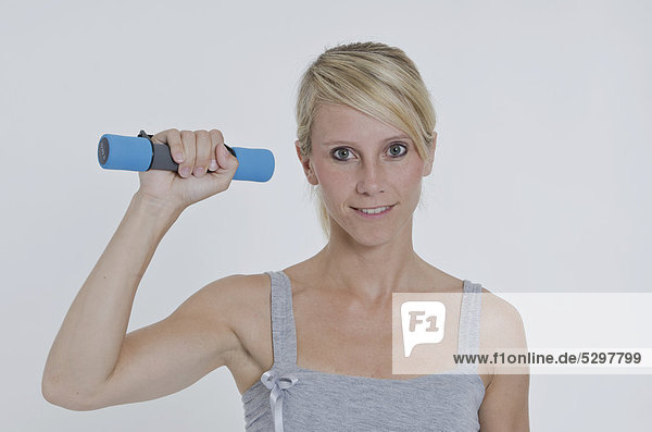 Young woman holding a small dumbbell in her right hand
