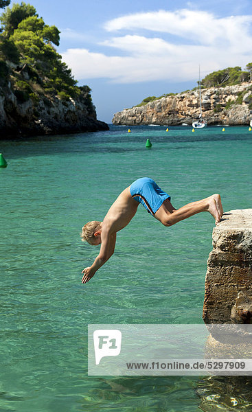 A boy jumping into the sea head-on Cala Pi southern coast of Majorca island Balearic Islands Spain Europe