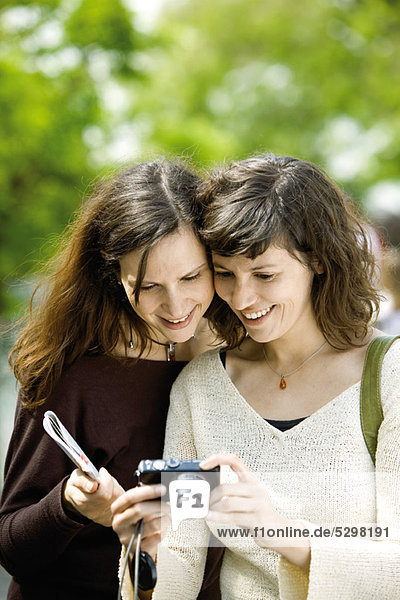 Frau zeigt Digitalkamera einem Freund
