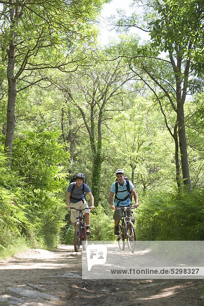 Men riding bicycles in woods