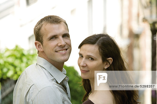Couple smiling over shoulders at camera  portrait