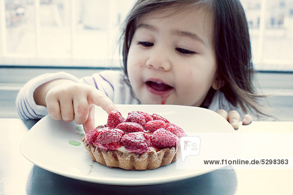 Little girl getting taste of raspberry tart
