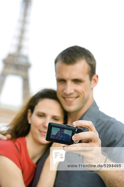 Couple photographing selves in front of Eiffel Tower  Paris  France