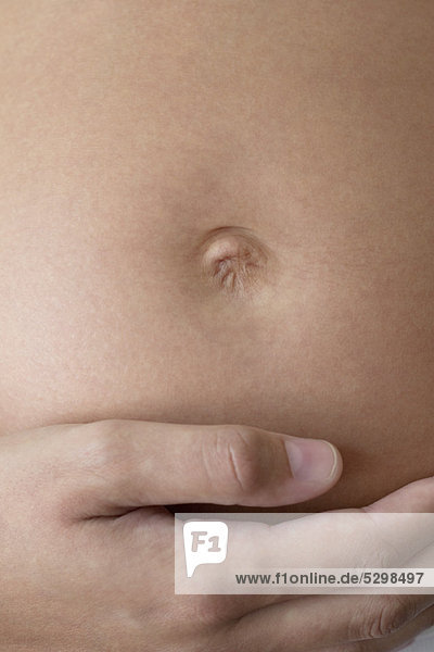 Nahaufnahme der Frauenhand auf dem schwangeren Bauch