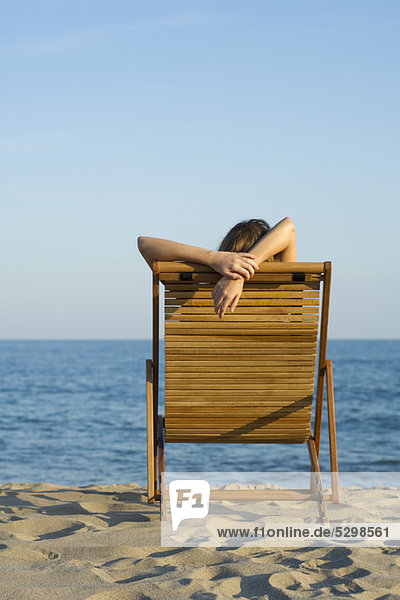 Frau entspannt sich im Liegestuhl am Strand