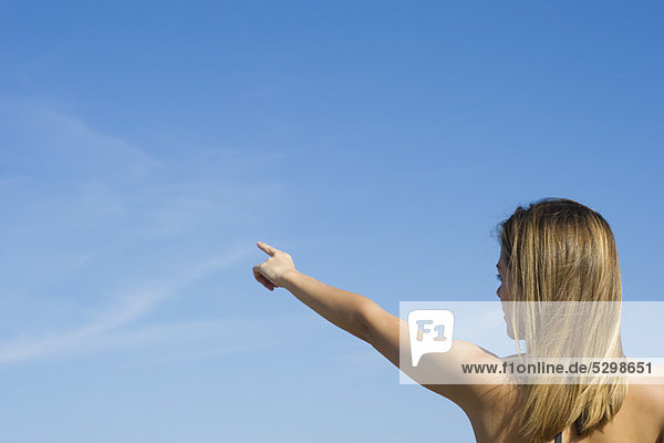 Frau zeigt auf den Himmel  Rückansicht