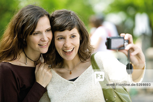 Woman photographing herself with friend