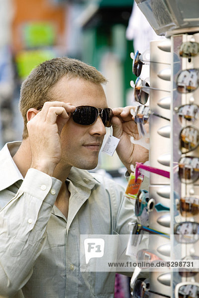 Mann probiert Sonnenbrille auf dem Straßenmarkt an