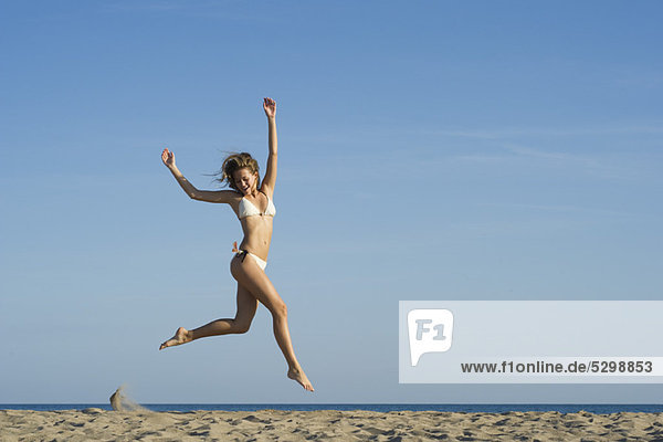 Frau beim Springen in der Luft am Strand