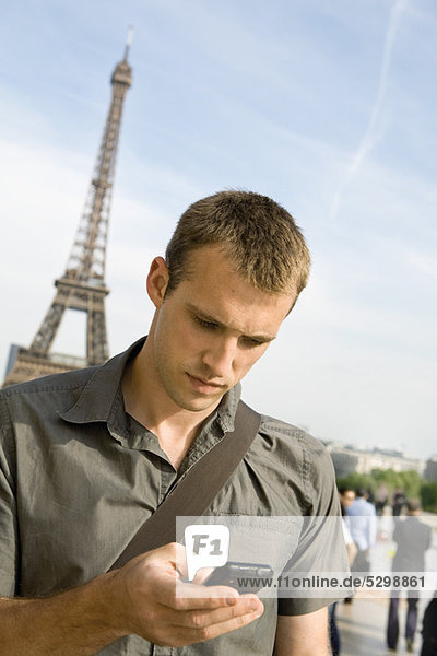 Mann SMS mit Handy  Eiffelturm im Hintergrund  Paris  Frankreich