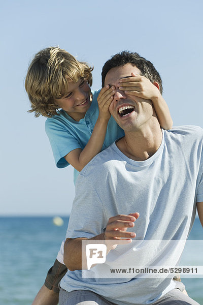 Boy covering father's eyes with hands
