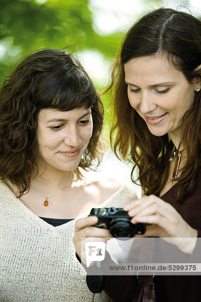 Woman showing digital camera to friend