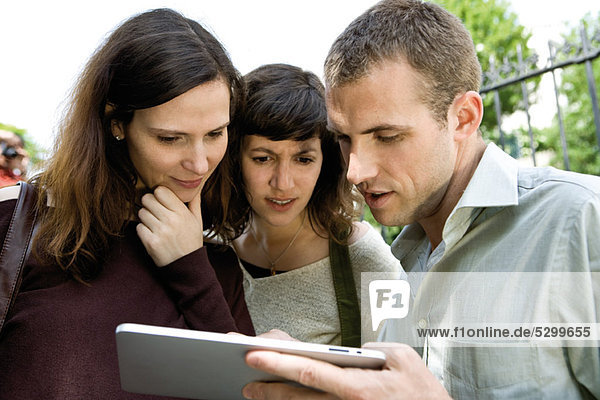 Friends looking at digital tablet outdoors