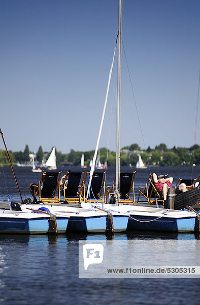 Segelboote und Bootssteg mit Liegestühlen an der Außenalster in St. Georg Hamburg Deutschland Europa