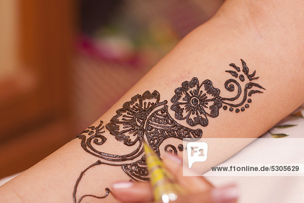 Applying traditional henna pattern on Indian bride's arm