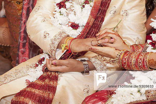 Indian bride passing wedding ring on her groom's finger