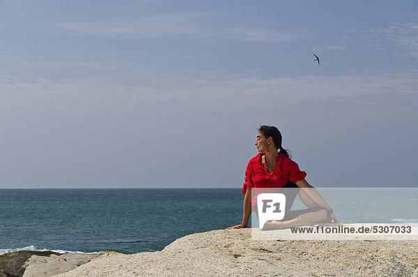 Woman in a yoga position  Ardha Matsyendrasana  by the sea in Kanyakumari  Tamil Nadu  India  Asia