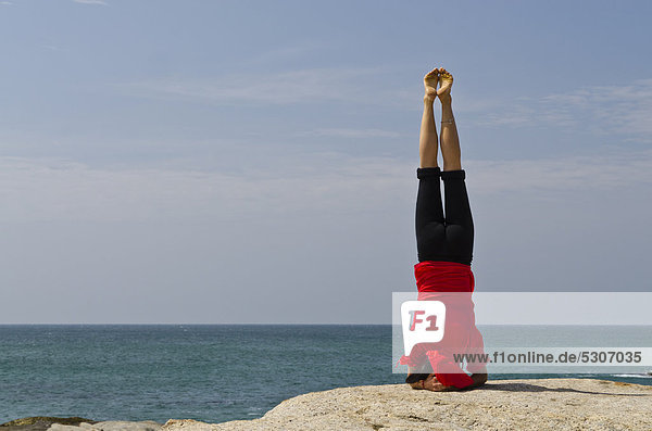 Woman in a yoga position  Sirshasana  by the sea in Kanyakumari  Tamil Nadu  India  Asia