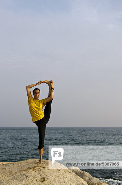 Woman in a yoga position  Anjaneyasana  by the sea in Kanyakumari  Tamil Nadu  India  Asia