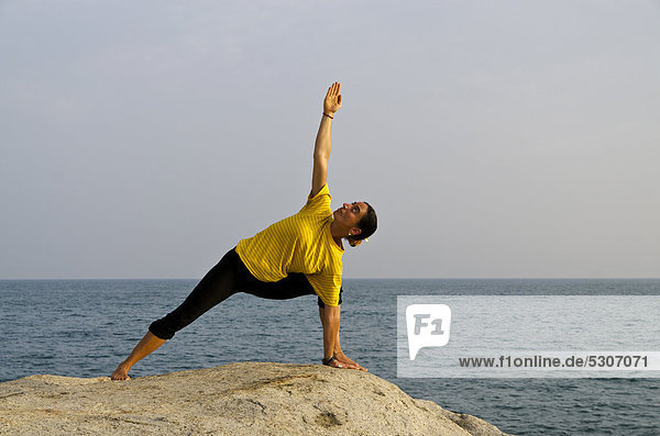 Woman in a yoga position  Utthita-Parshvakonasana  by the sea in Kanyakumari  Tamil Nadu  India  Asia