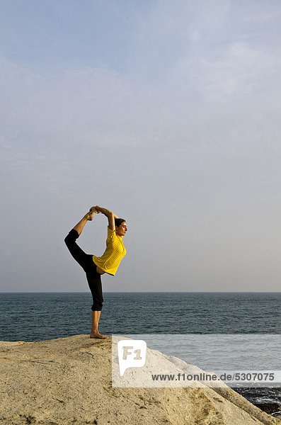 Woman in a yoga position  Natarajasana  by the sea in Kanyakumari  Tamil Nadu  India  Asia