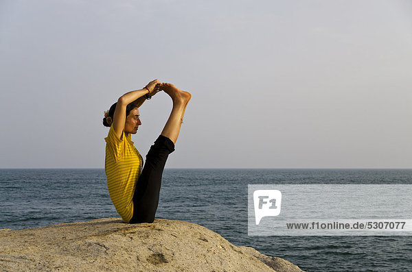 Woman in a yoga position  a variation of Paschimothanasana  by the sea in Kanyakumari  Tamil Nadu  India  Asia