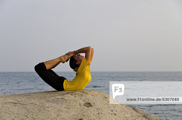 Woman in a yoga position  Dhanurasana  by the sea in Kanyakumari  Tamil Nadu  India  Asia