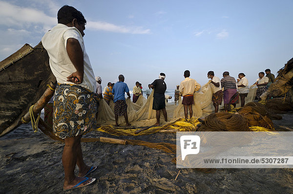 Fischer beim Fischen auf traditionelle Art und Weise in einem kleinen Dorf an der Küste bei Varkala  Kerala  Indien  Asien