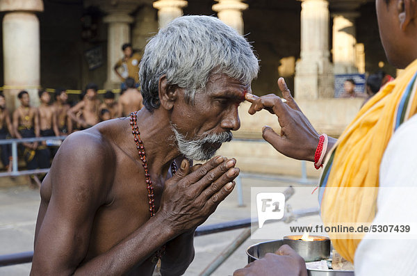 Pilgrim receives the blessings of Bahubali by a local priest on Indragiri hill in Sravanabelagola  Karnataka  India  Asia