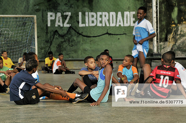 Teenagers and children on a playground  wall with lettering Paz Liberdade  Portuguese for Peace Freedom at the back  Favela Morro da Formiga slum  Tijuca district  Rio de Janeiro  Brazil  South America