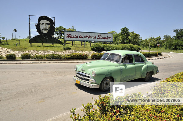 Oldtimer vor Revolutions-Propaganda  Hasta la victoria siempre  mit Portrait von Ernesto ChÈ Guevara  Las Tunas  Kuba  Karibik