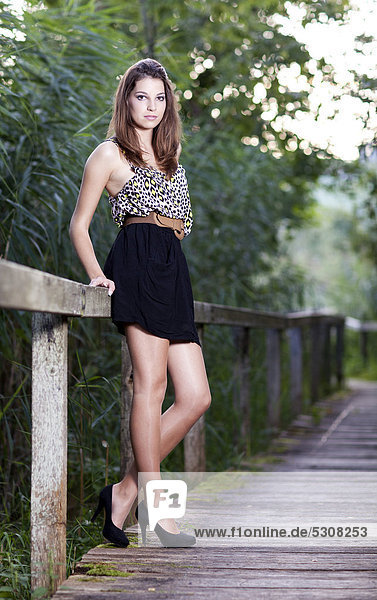 Junge Frau mit Minirock posiert auf Holzsteg