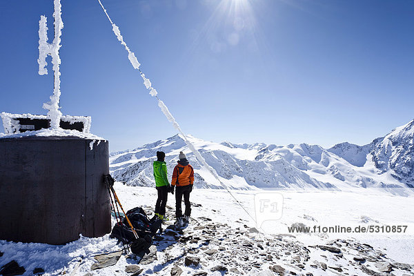 Skitourengeher auf dem Gipfel der hinteren Schöntaufspitze mit der Wetterstation  Sulden im Winter  hinten die Zufallspitze und der Cevedale  Südtirol  Italien  Europa