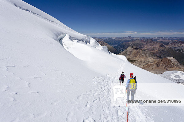 Climbers passing through the glacial landscape while descending Piz Palue  Grisons  Switzerland  Europe