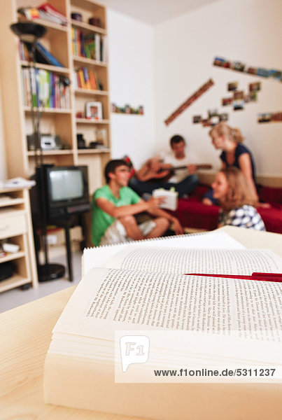 Aufgeschlagenes Buch und Studenten in Studentenwohnheim