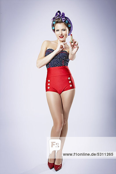 Young woman with curlers wearing hot pants holding a red lipstick  pin-up