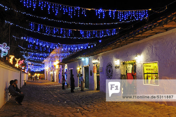 Alleyway with chains of lights in Villa de Leyva in the evening  colonial buildings  Boyaca department  Colombia  South America