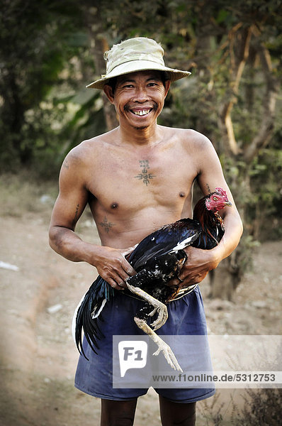 Lachender Mann mit Huhn  Kambodscha  Südostasien  Asien