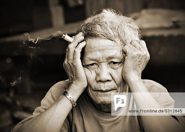 Alter  nachdenklicher Mann mit Zigarre hält sich den Kopf  Laos  Südostasien  Asien