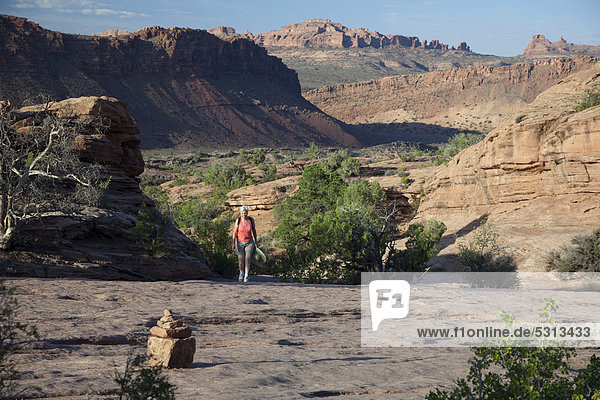 Susan Newell  62  wandert zum Delicate Arch Felsenbogen im Arches-Nationalpark  ein Steinmännchen im Vordergrund markiert den Weg  Moab  Utah  USA