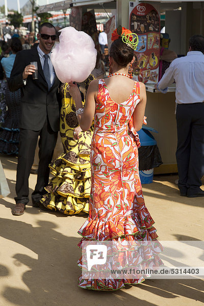 Junge Frau in Flamencokleid und mit Zuckerwatte bei der Festwoche Feria de Abril in Sevilla  Andalusien  Spanien  Europa