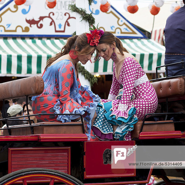 Zwei junge Frauen in Flamencokleidern auf einer Kutsche bei der Festwoche Feria de Abril in Sevilla  Andalusien  Spanien  Europa