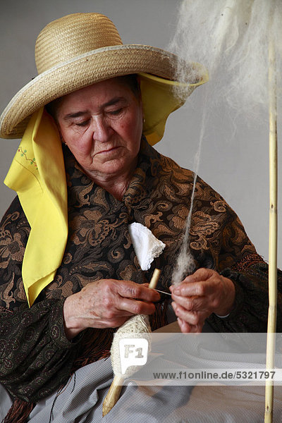 Ältere spinnende Frau in traditioneller Tracht bei einem Kunsthandwerksmarkt  Ibiza  Spanien  Europa