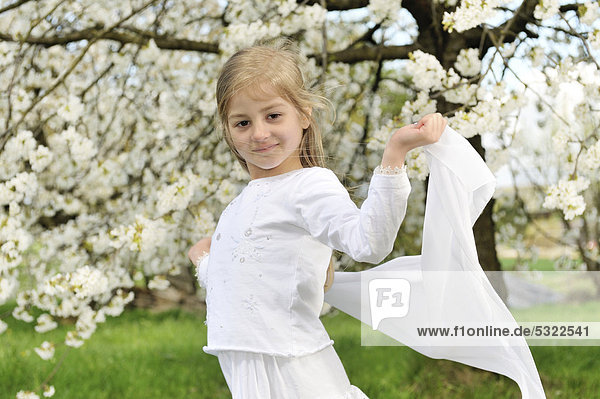 Mädchen  6 Jahre  vor blühendem Baum im Frühling