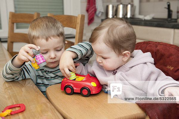 Zwei Kinder  3 und 1 Jahre  spielen miteinander mit einem Spielzeugauto