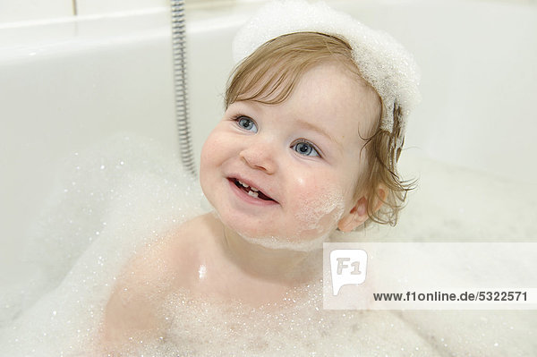 Einjähriges Mädchen spielt mit Schaum in der Badewanne  Portrait
