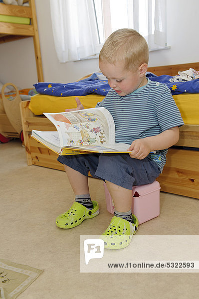 Boy  3 years  leafing through a book in the children's room