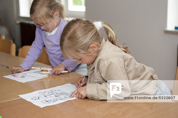 Zwei Mädchen  5 und 4 Jahre  malen am Tisch