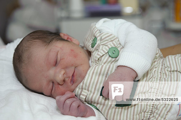 Neugeborenes kurz nach Geburt  lächelt im Schlaf
