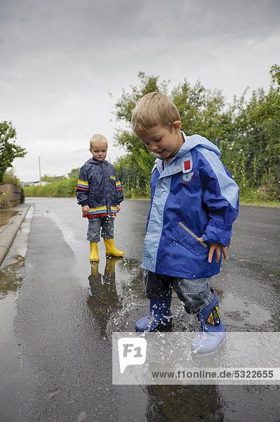 4jähriger Junge springt in einer Pfütze auf der Straße im Regen  Assamstadt  Baden-Württemberg  Deutschland  Europa